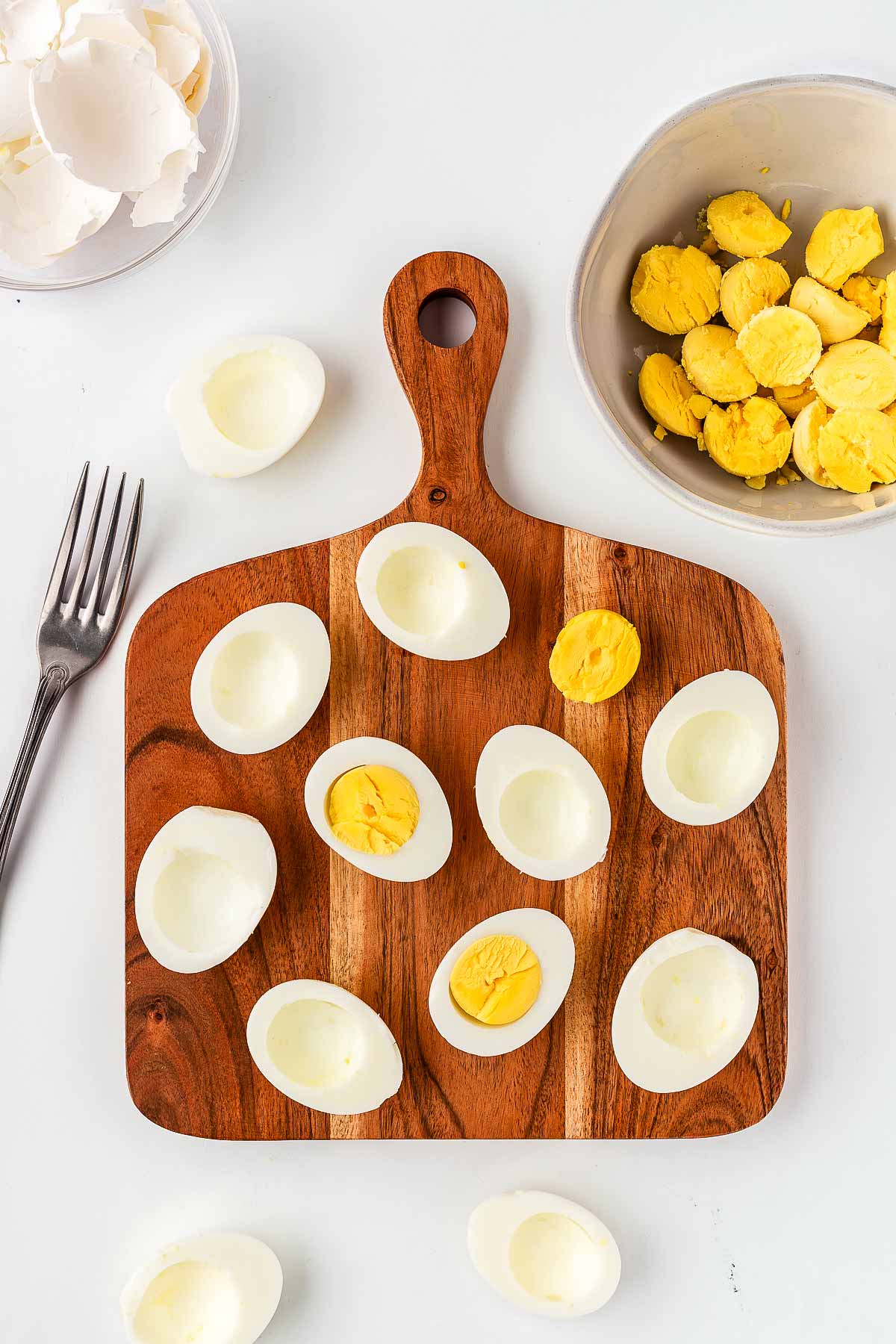 overhead view of halved hard boiled eggs on wooden cutting board