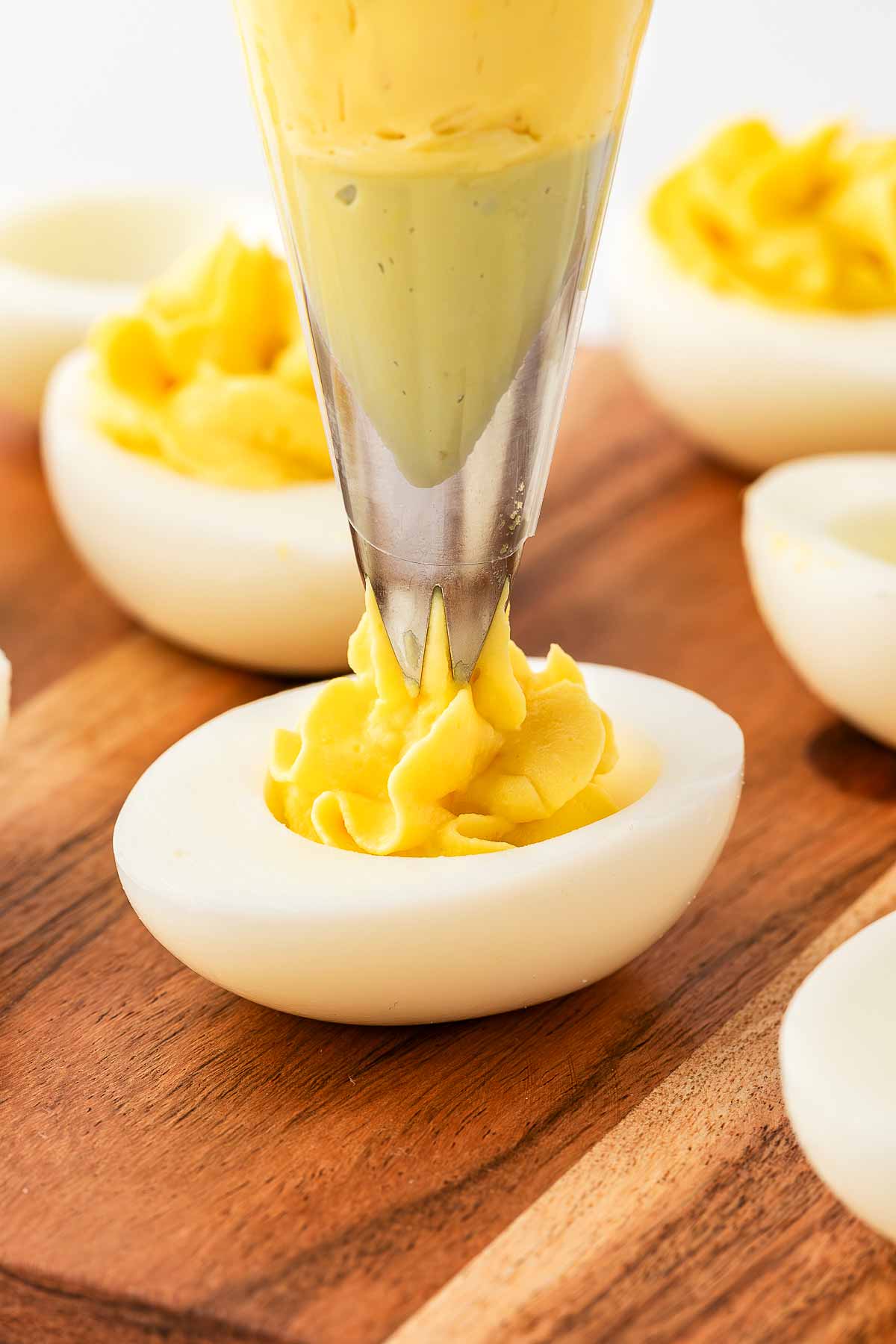 close up view of deviled egg filling being piped into egg white halves