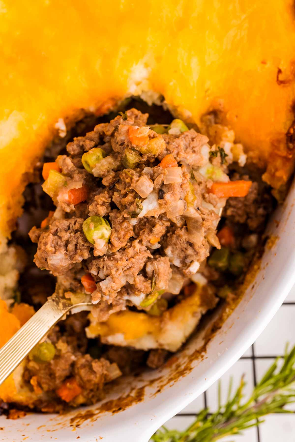 overhead close up view of spoon scooping shepherd's pie from white dish