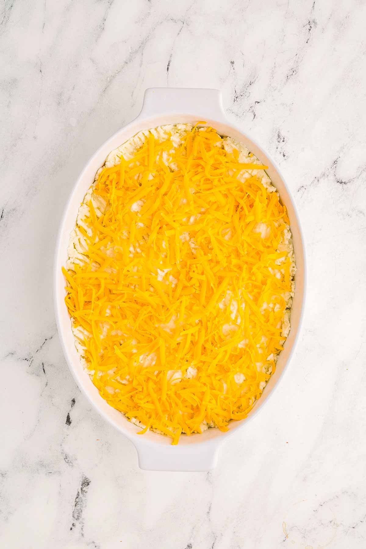 overhead view of unbaked shepherd's pie in white oval casserole dish