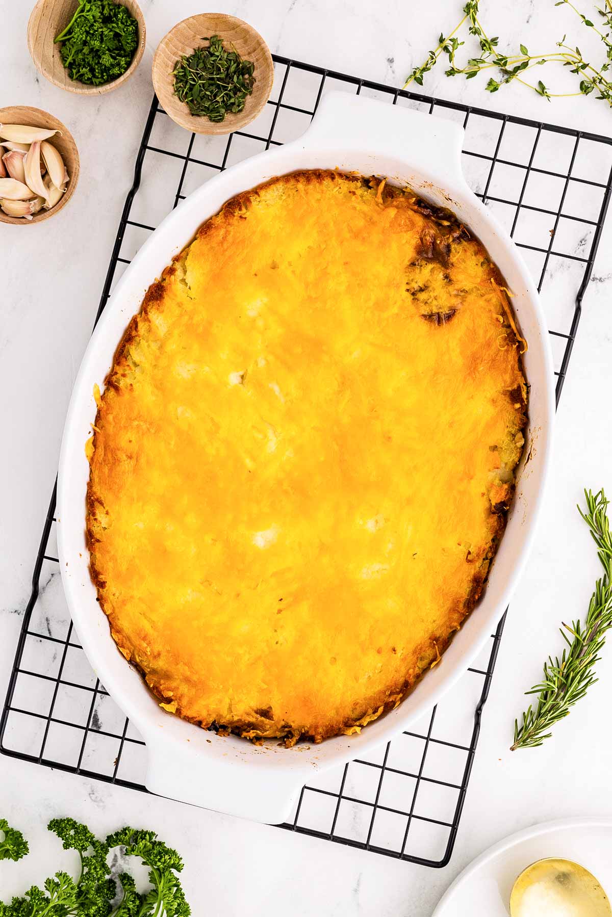 overhead view of baked shepherd’s pie with golden cheese crust on wire rack