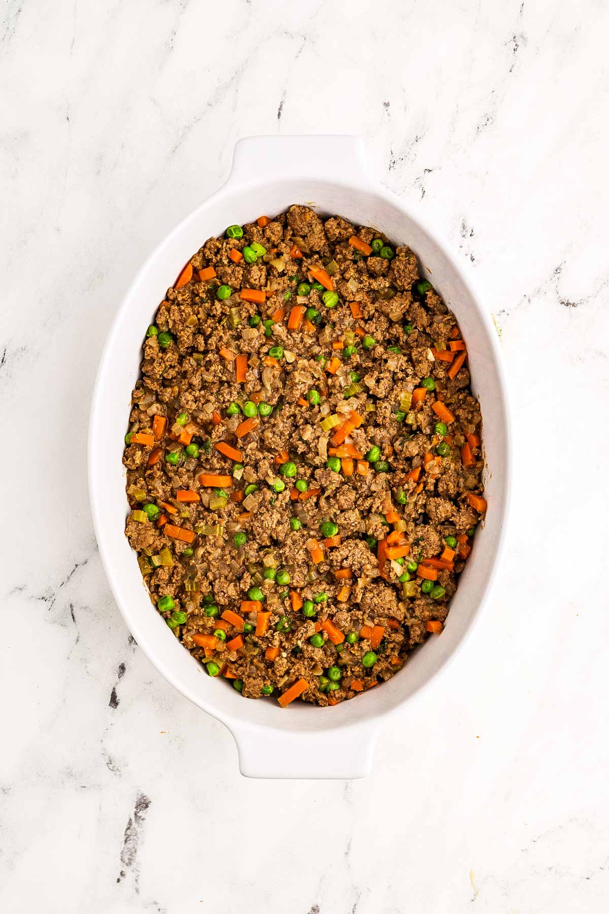 overhead view of cooked shepherd's pie filling spread in white oval baking dish