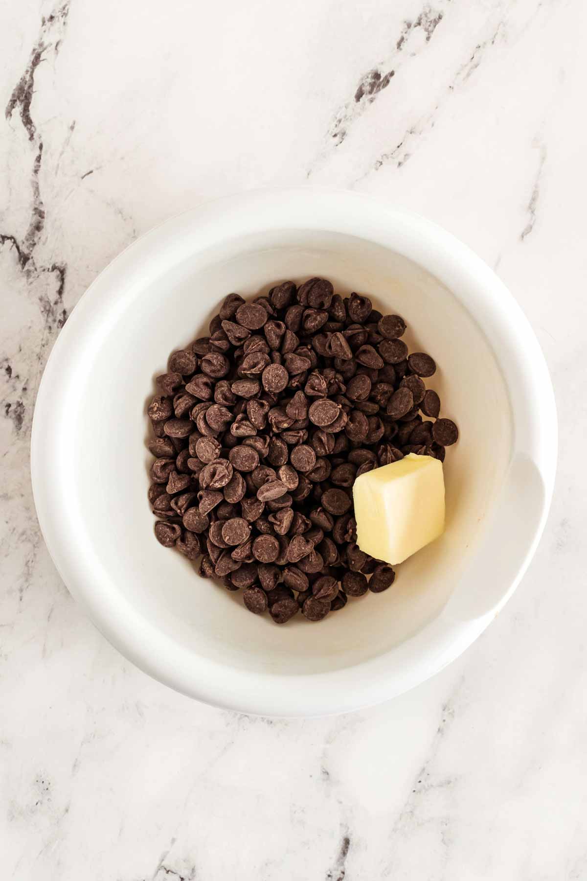 overhead view of chocolate chips and butter in a small white bowl