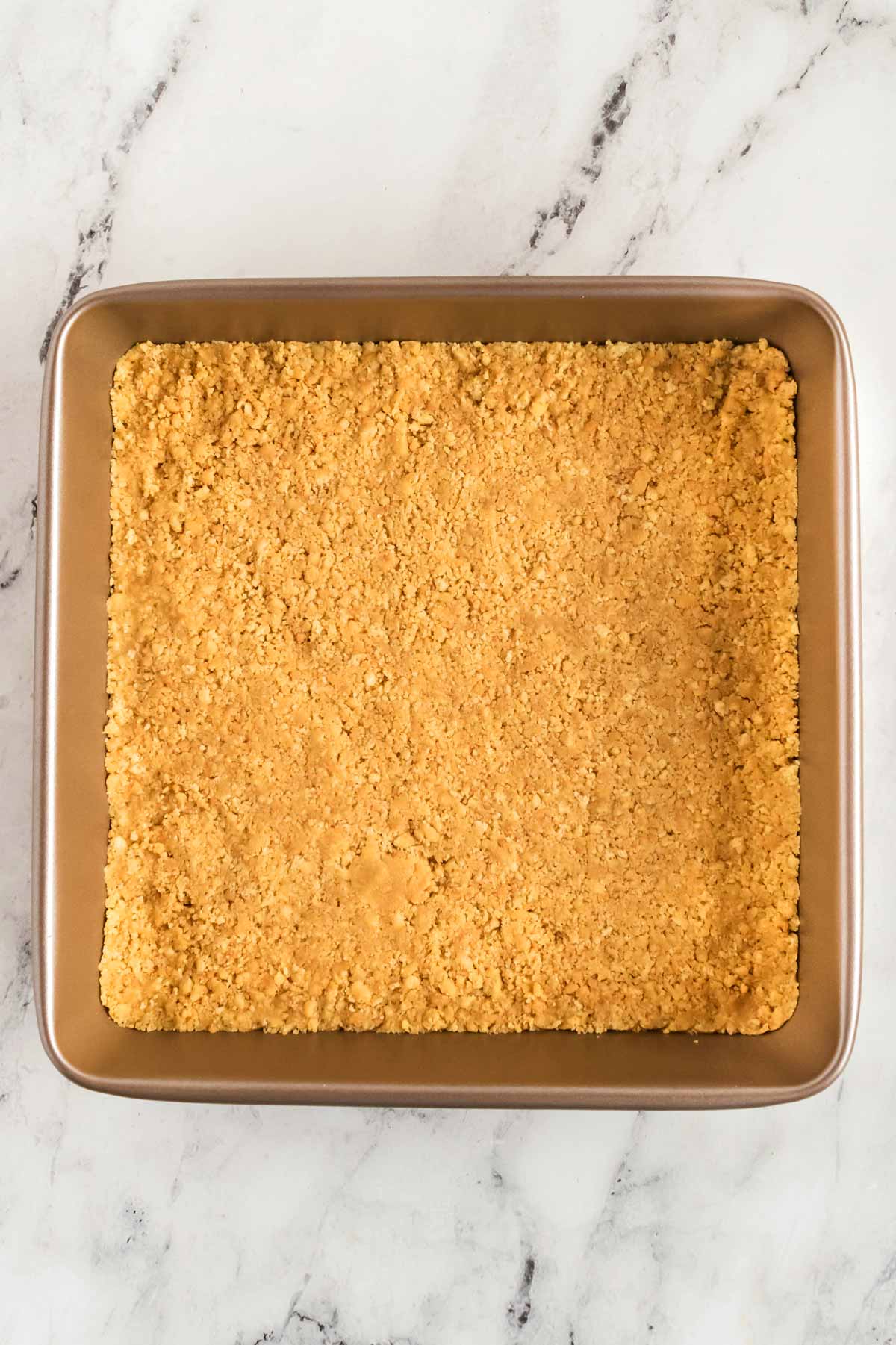 overhead view of cookie crumbs pressed into square pan