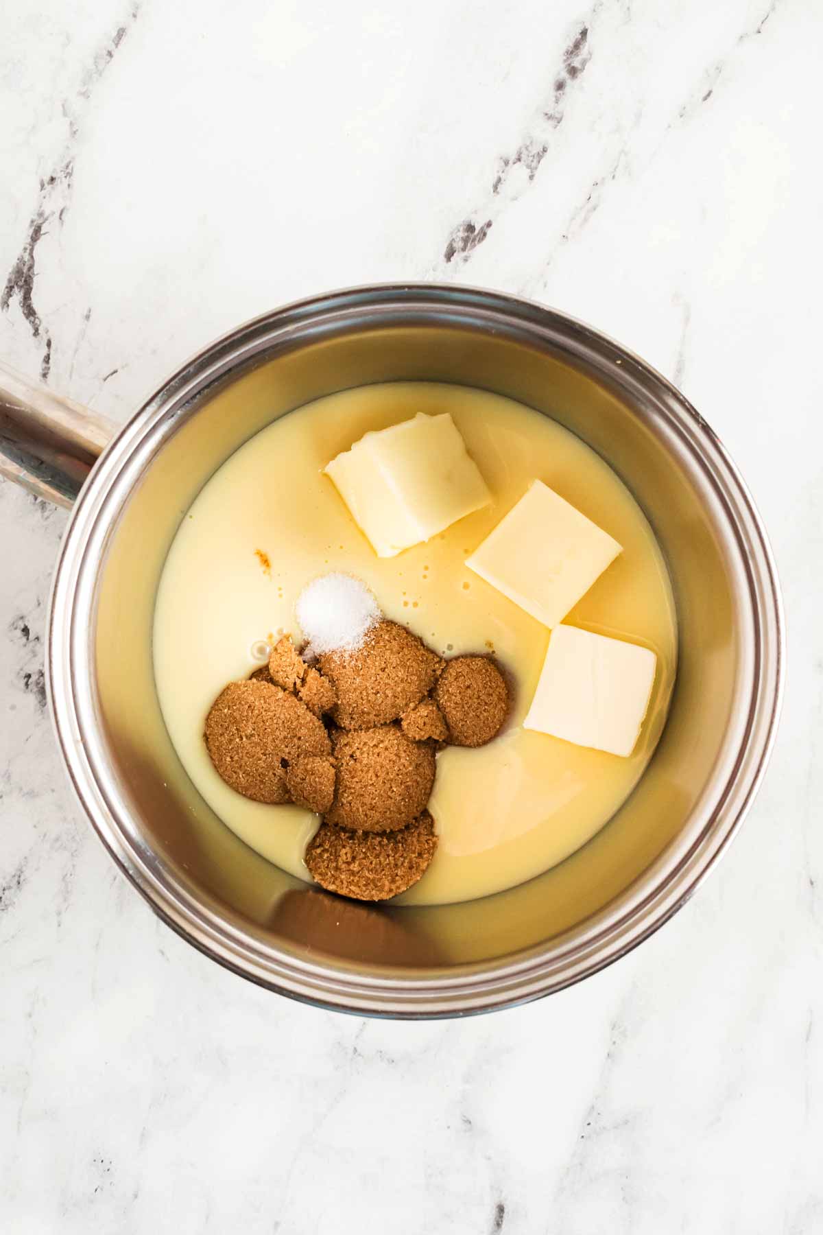 overhead view of butter, brown sugar and condensed milk in small saucepan