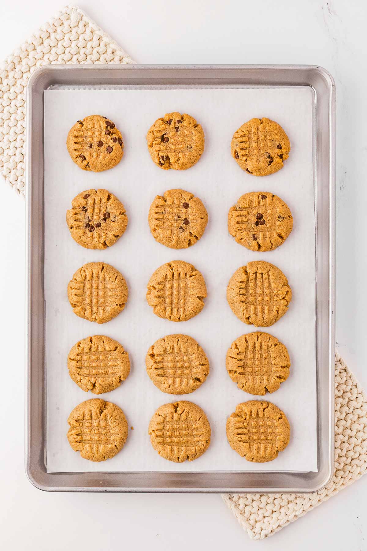 overhead view of baked peanut butter cookies on lined baking sheet