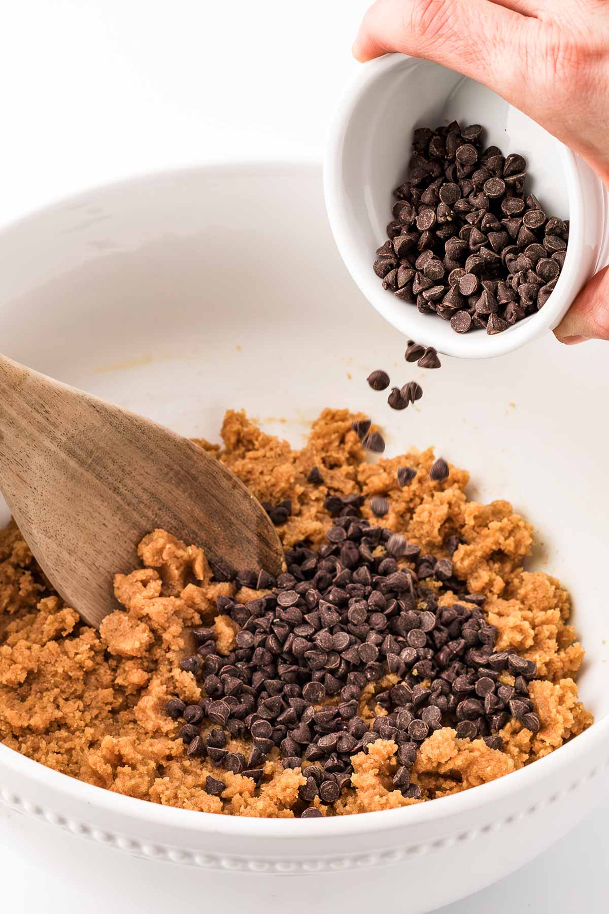 frontal view of chocolate chips being added to bowl of cookie dough