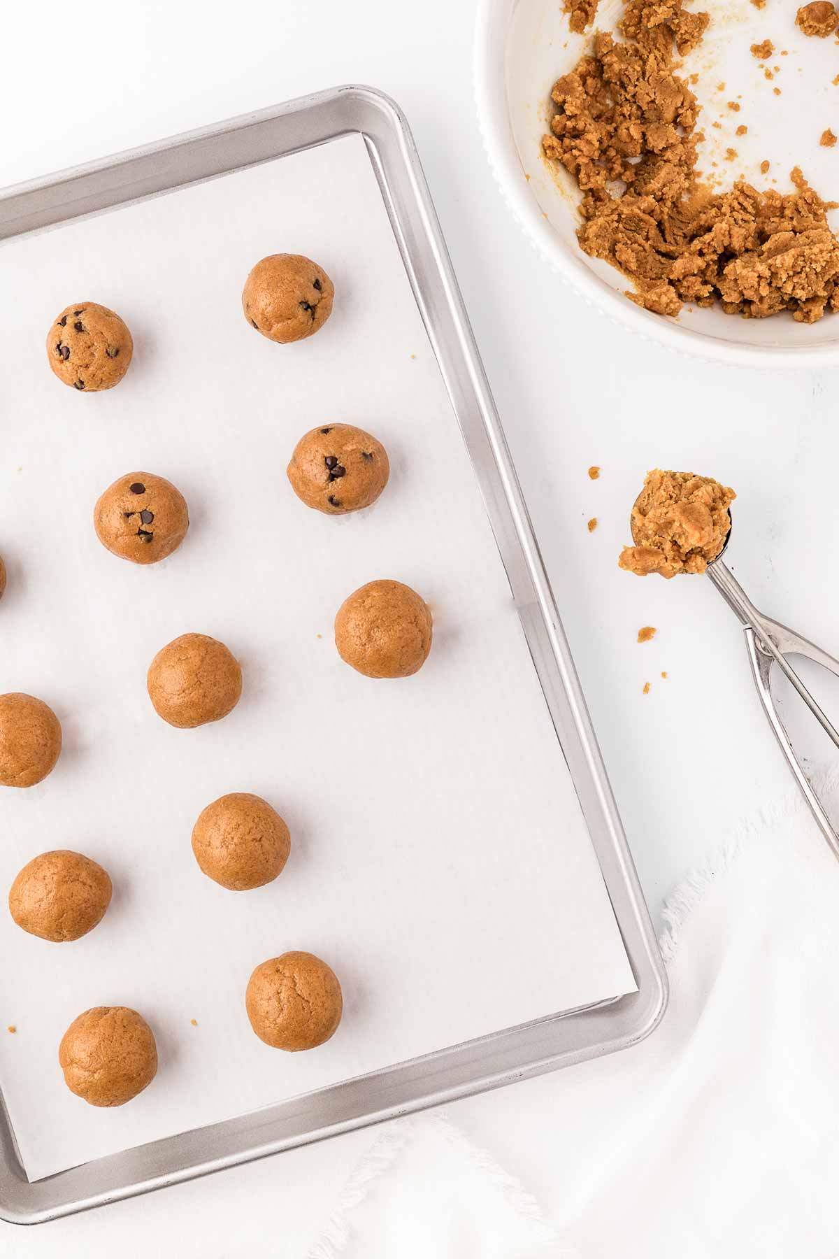 overhead view of cookie dough balls on lined baking sheet