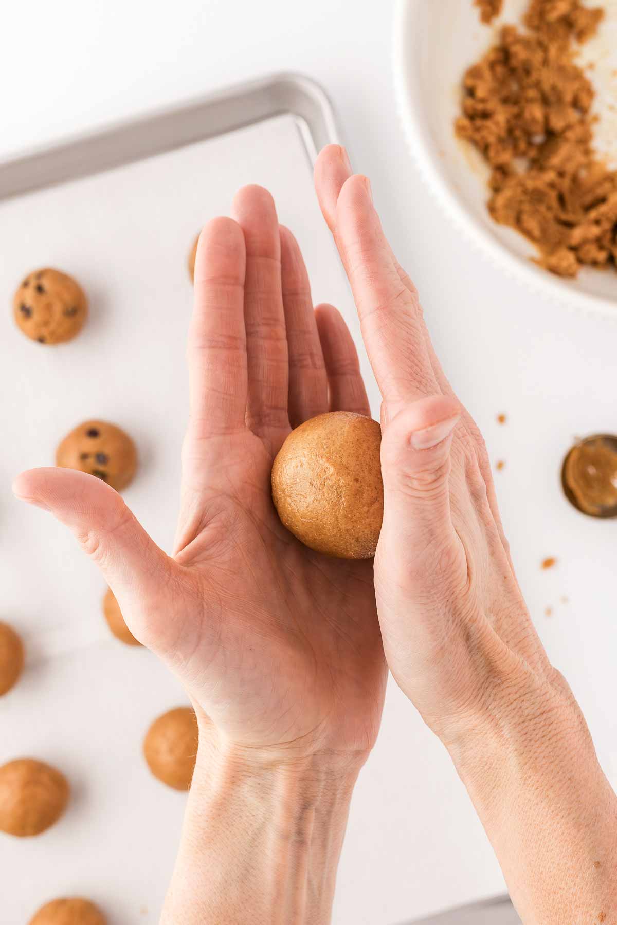 female hands rolling peanut butter cookie dough into ball