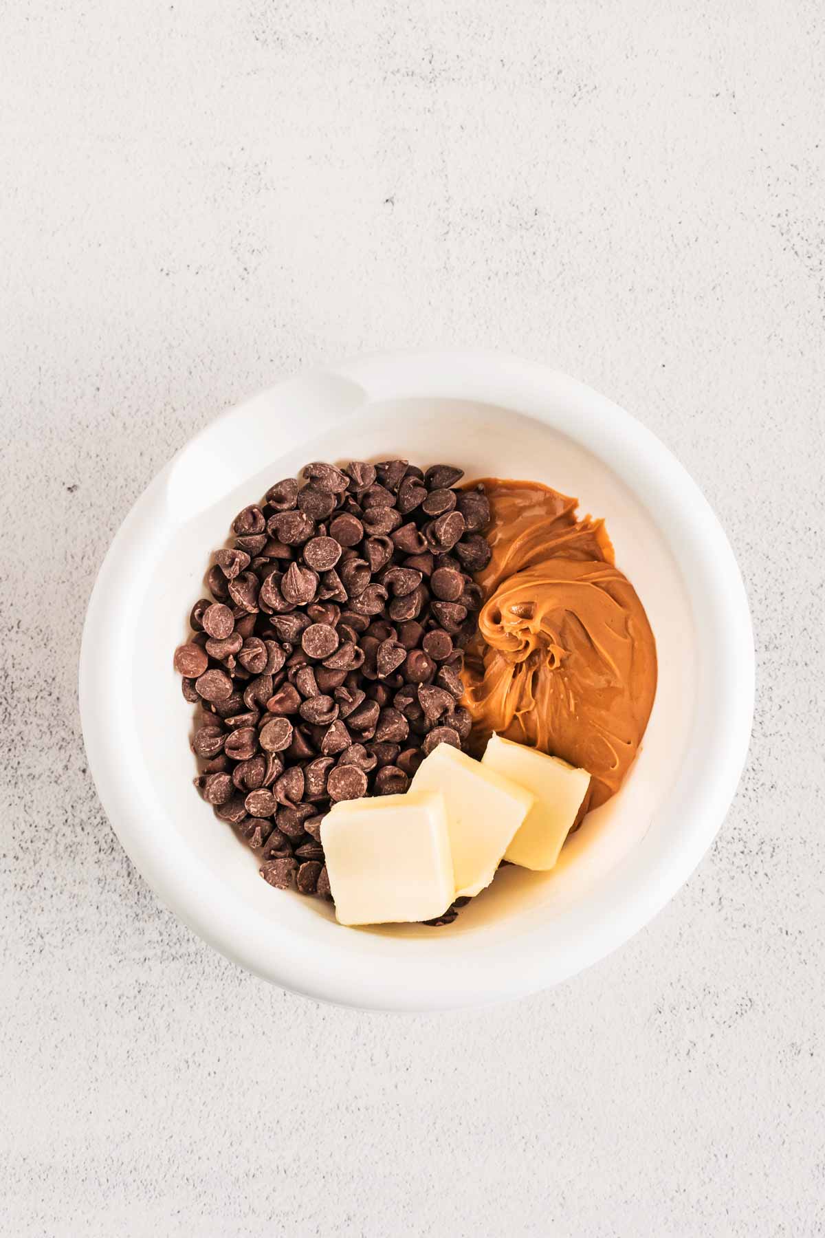 overhead view of chocolate chips, peanut butter and butter in small bowl