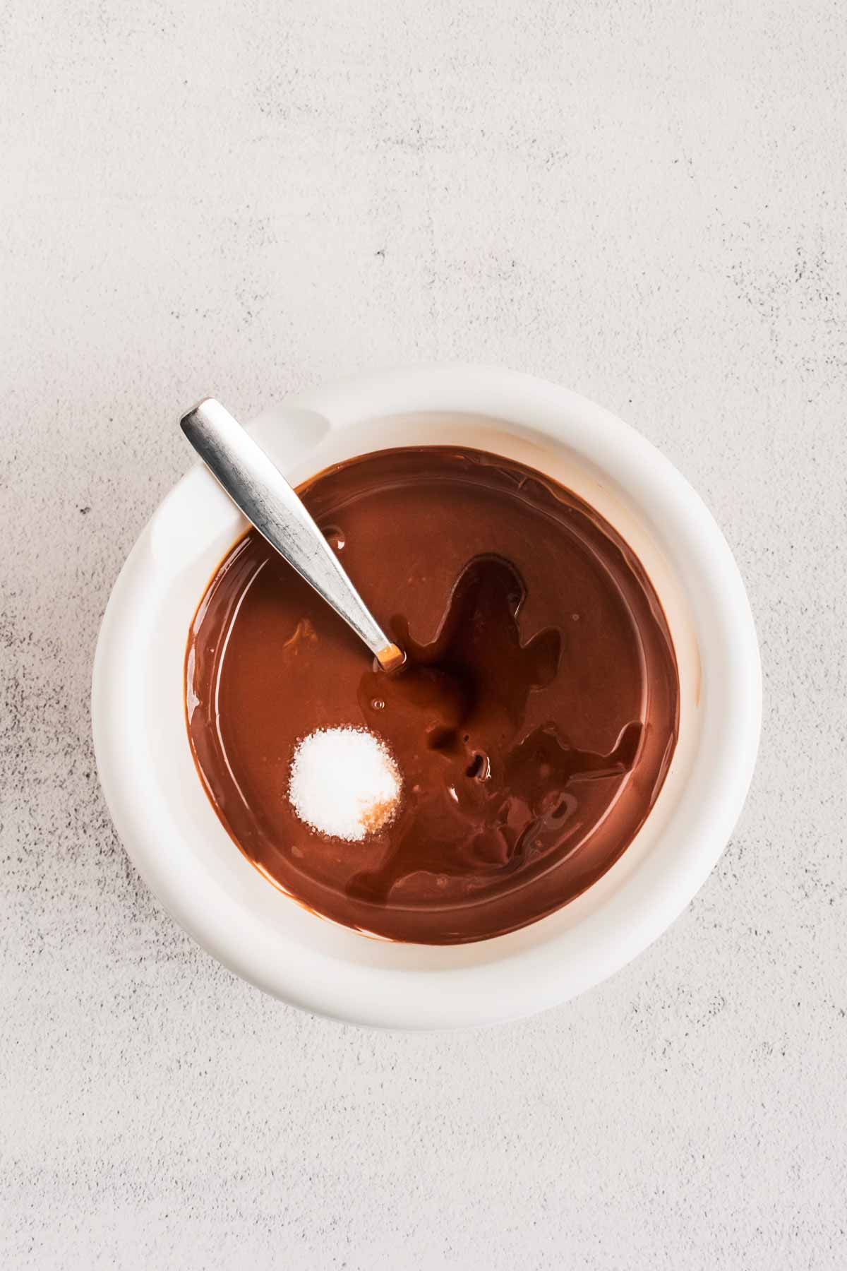 overhead view of melted chocolate with salt and vanilla in small white bowl