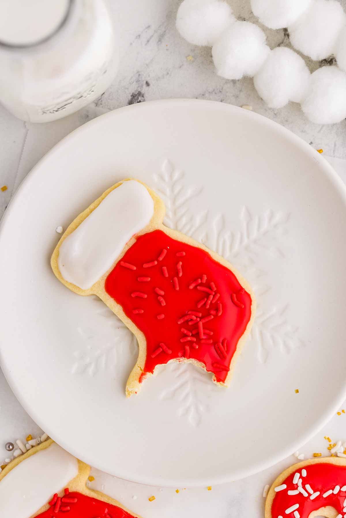 overhead view of decorated sugar cookie with bite taken out on white plate