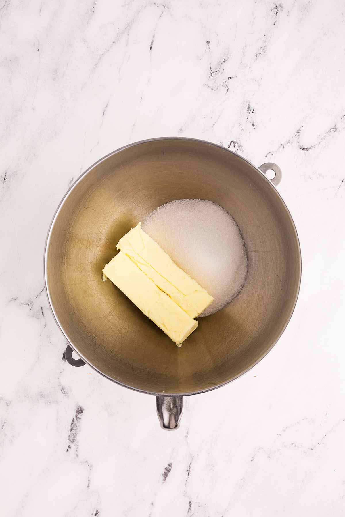 overhead view of sugar and butter in stand mixer bowl