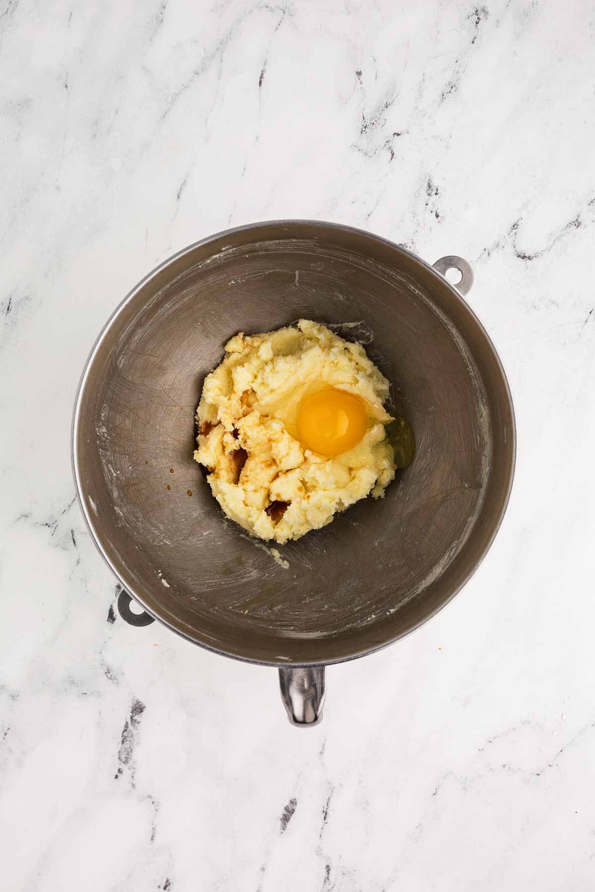 overhead view of creamed butter and sugar with cracked egg