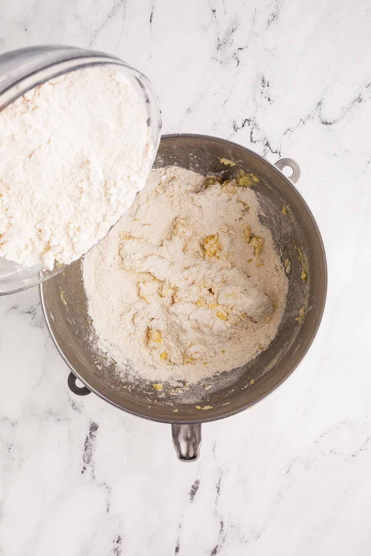 flour being mixed into creamed cookie ingredients in stand mixer bowl