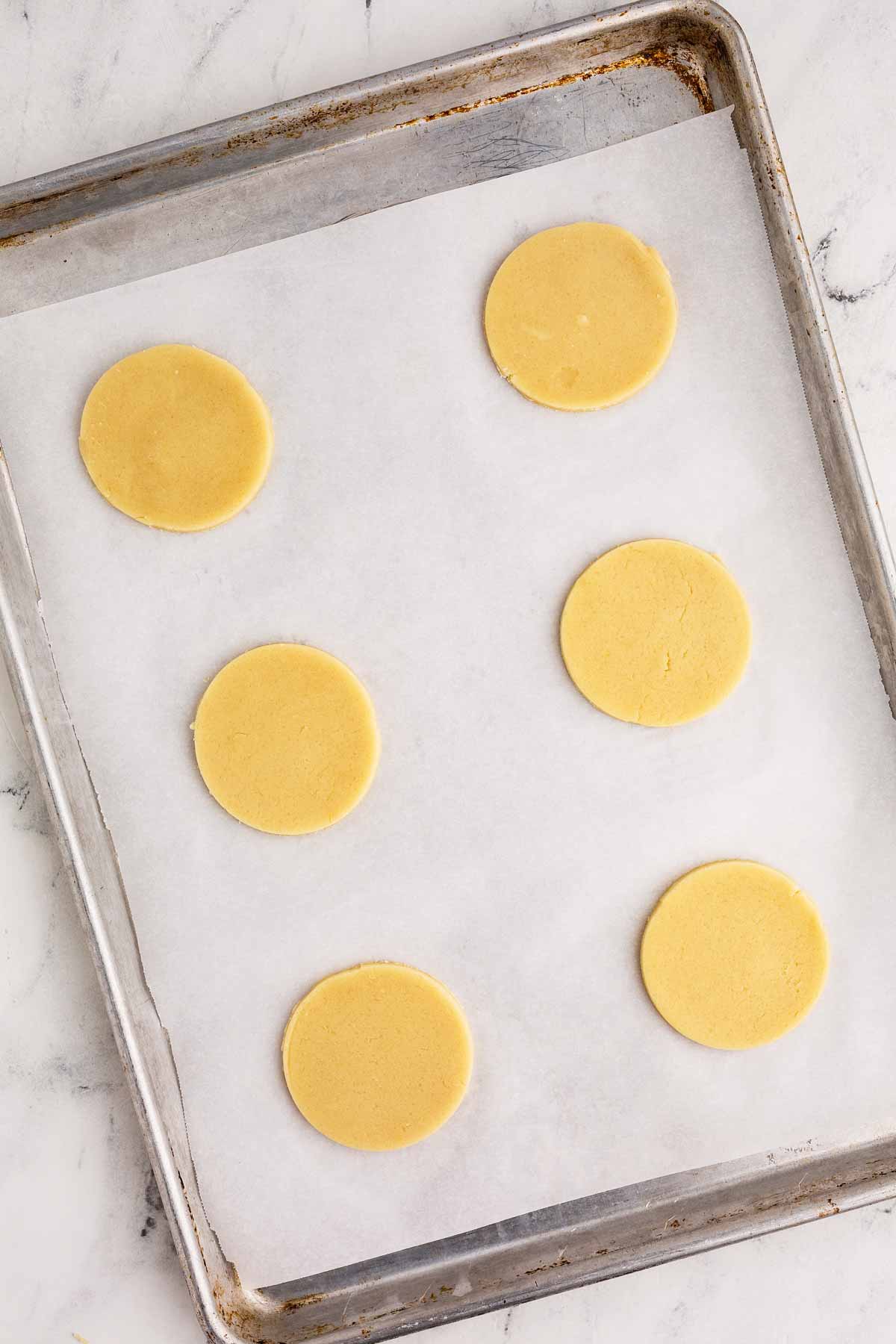 overhead view of cut out sugar cookie circles on lined baking sheet