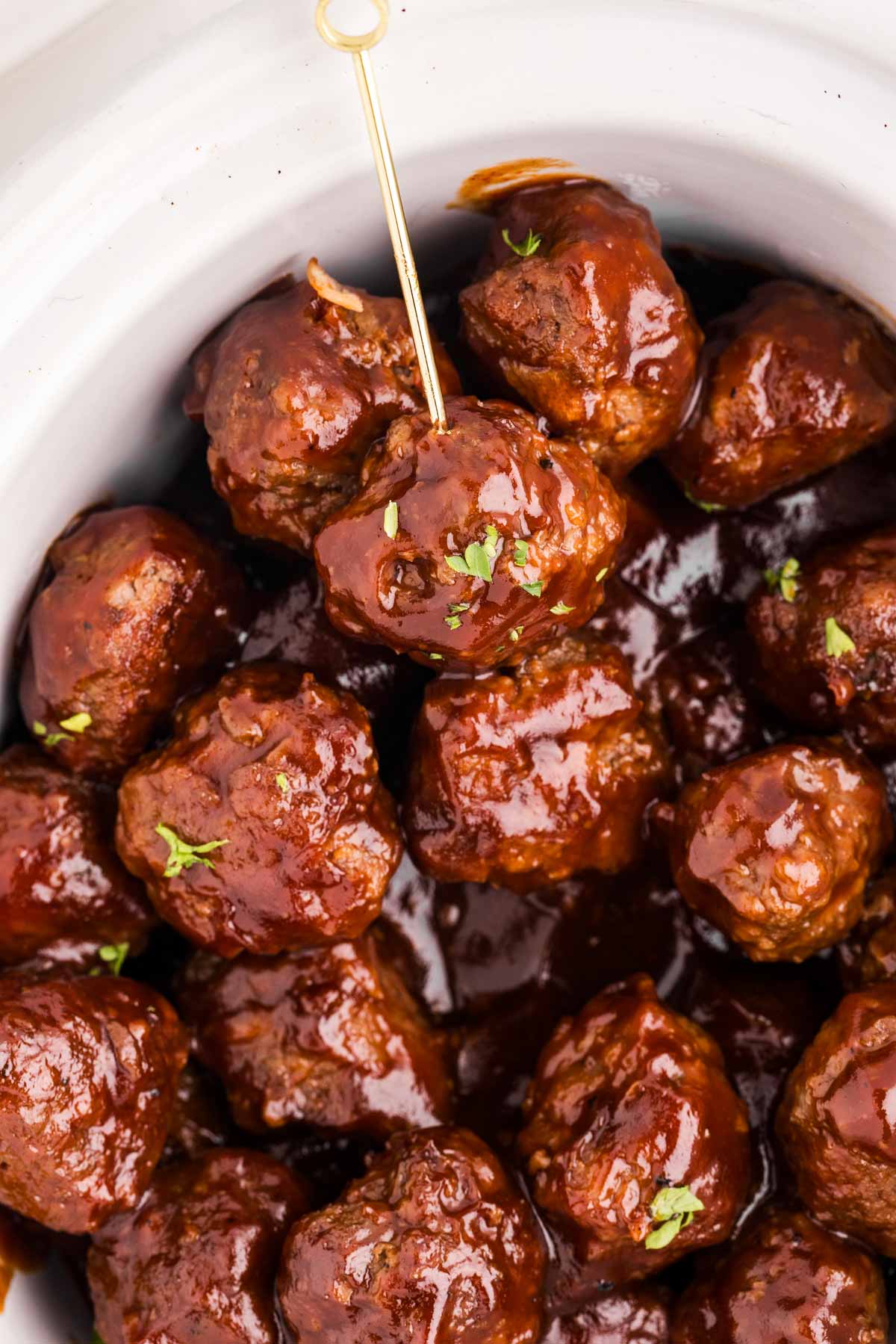 overhead close up view of sticky bbq meatballs in slow cooker with toothpick