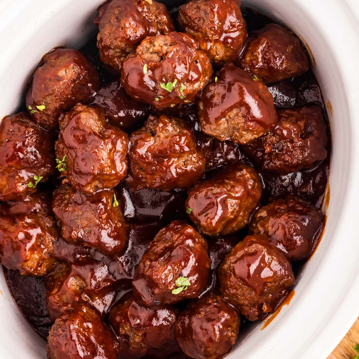 overhead close up view of bbq meatballs in white crock of slow cooker