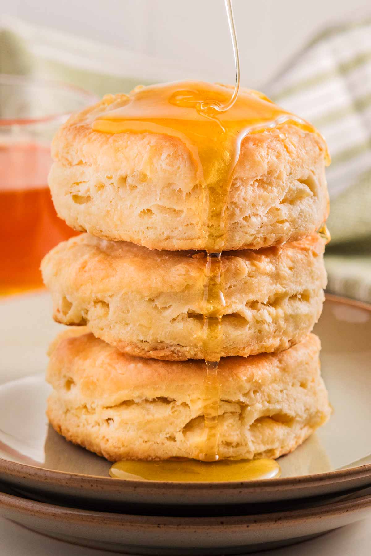 frontal view of three biscuits stacked with honey drizzling over them