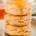 frontal view of three biscuits stacked with honey drizzling over them