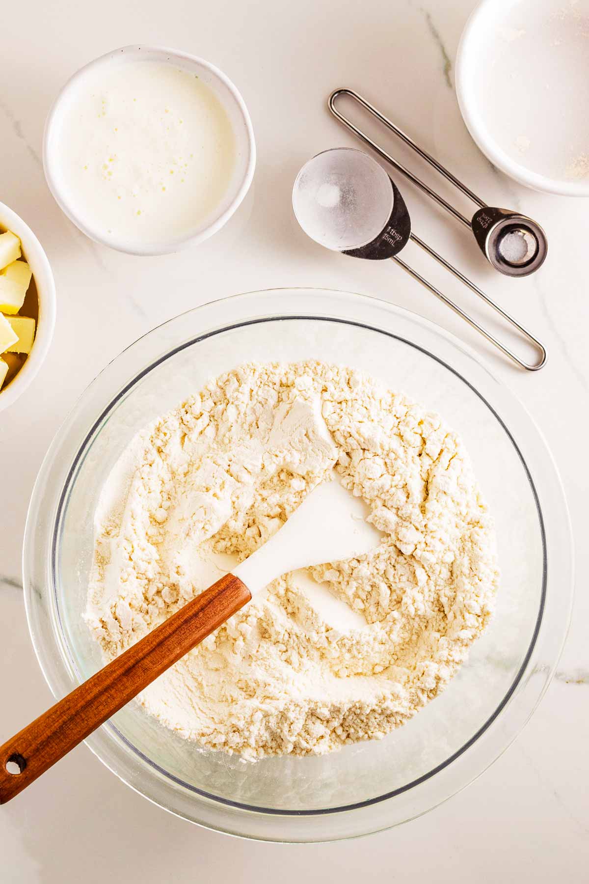 overhead view of flour in glass bowl with spatula stuck in