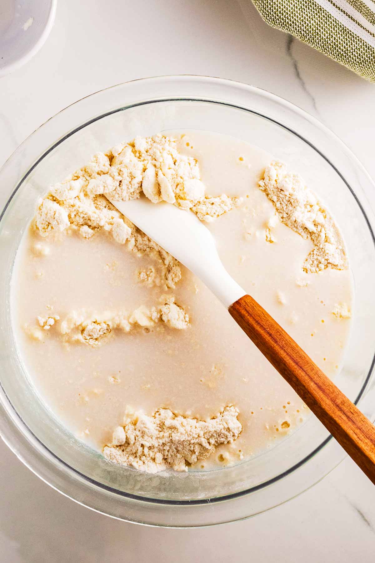 overhead view of buttermilk and flour in glass bowl with spatula