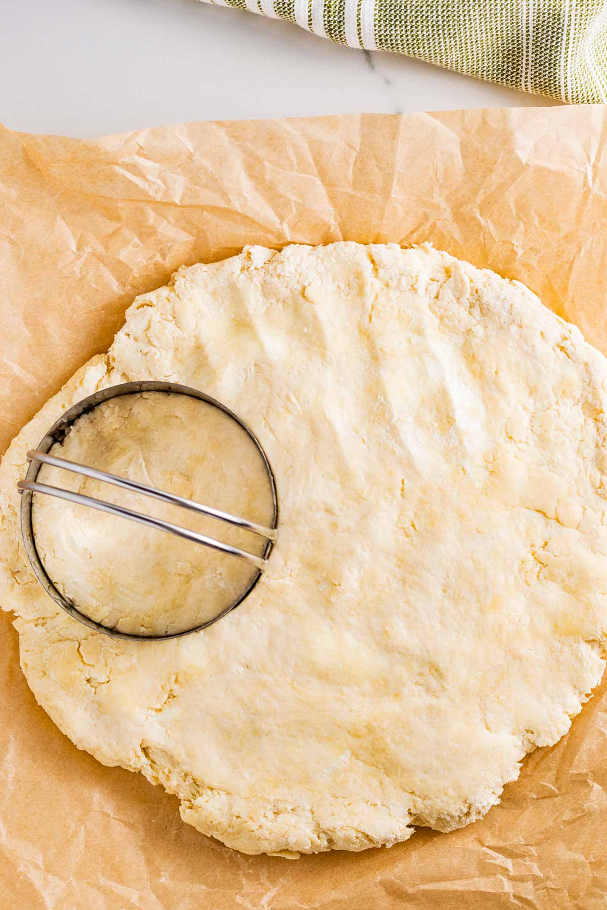 overhead view of biscuit cutter on top of biscuit dough