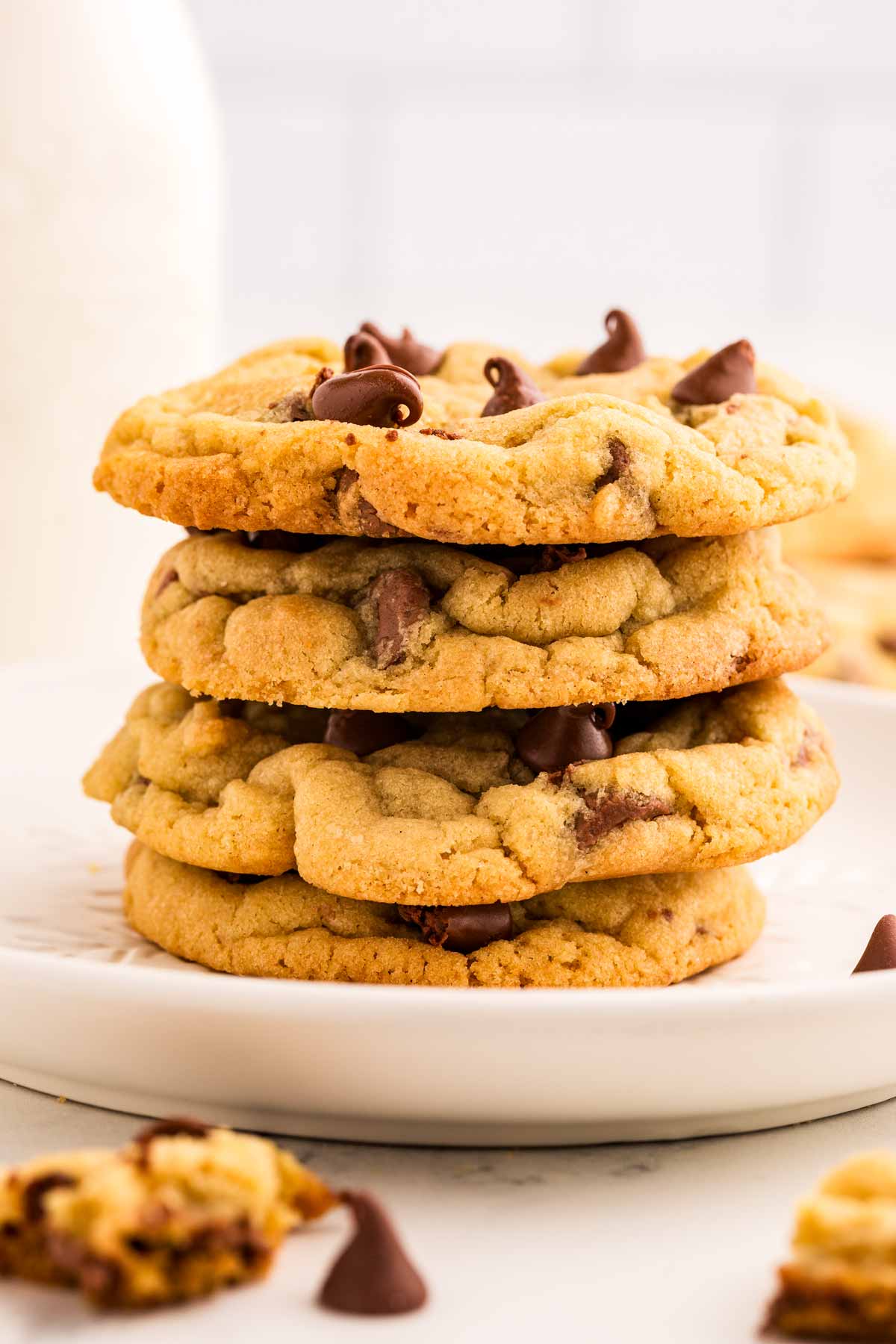 stack of chocolate chip cookies in front of milk bottle