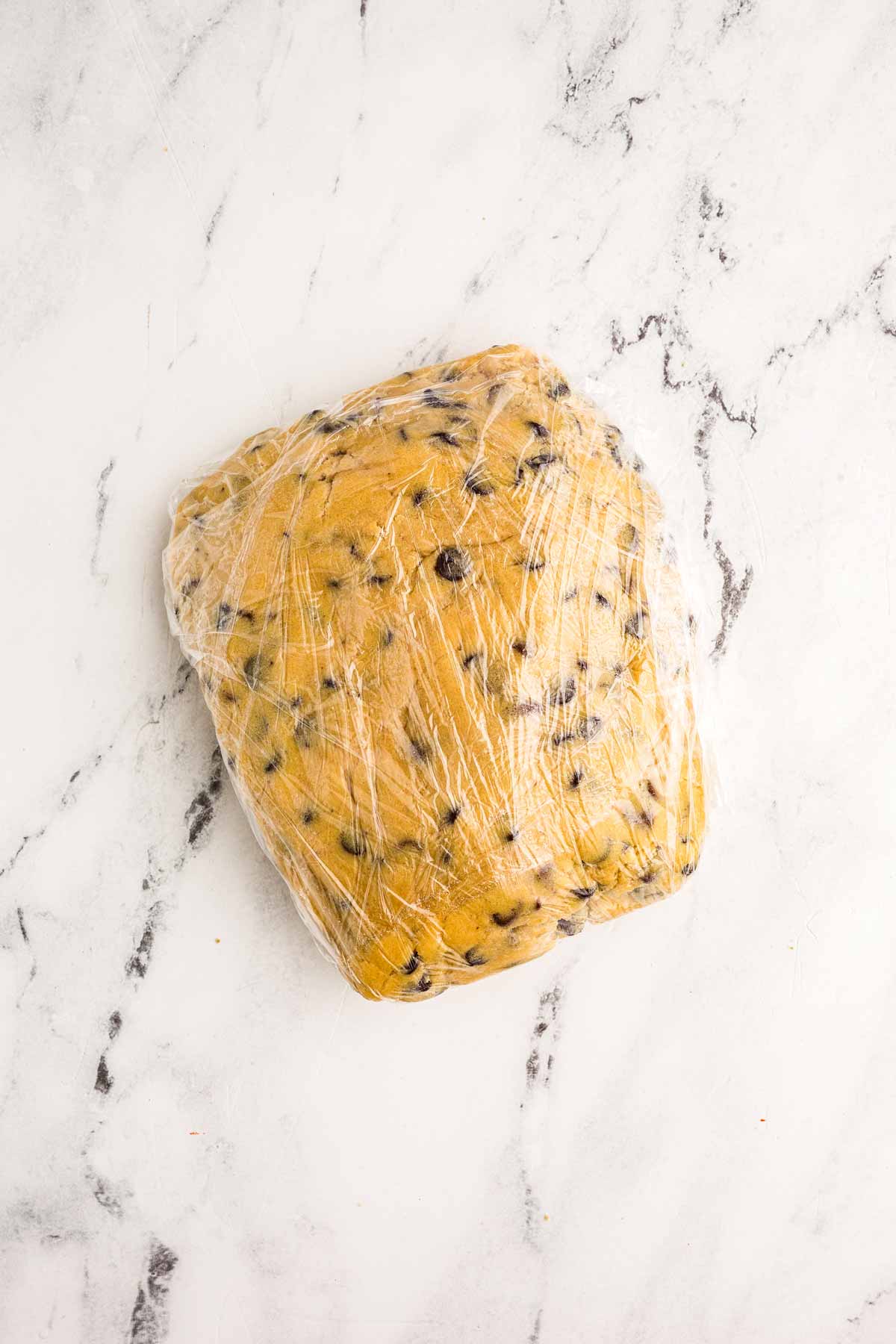 overhead view of chocolate chip cookie dough wrapped in plastic wrap