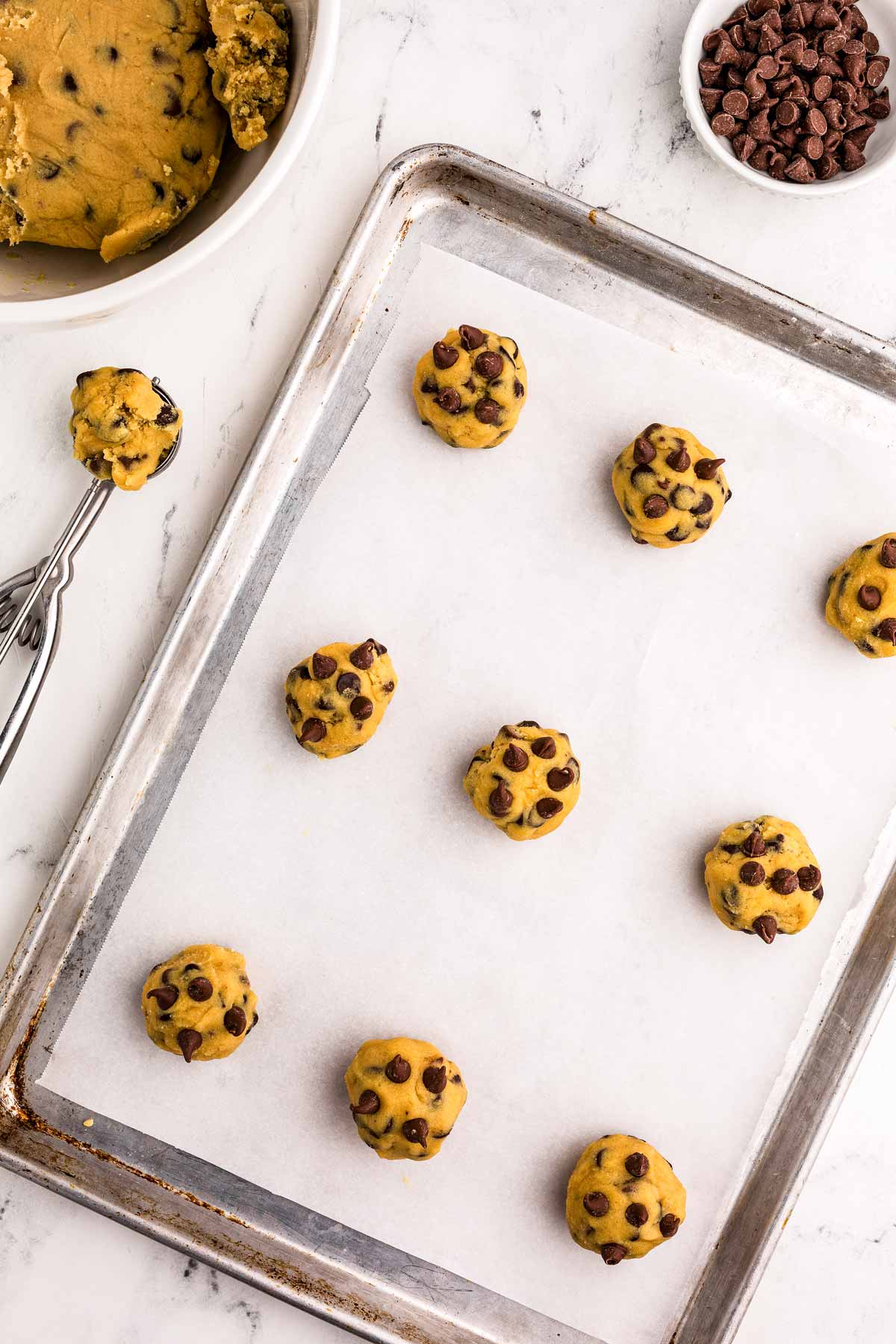 overhead view of chocolate chip cookie dough balls on lined baking sheet