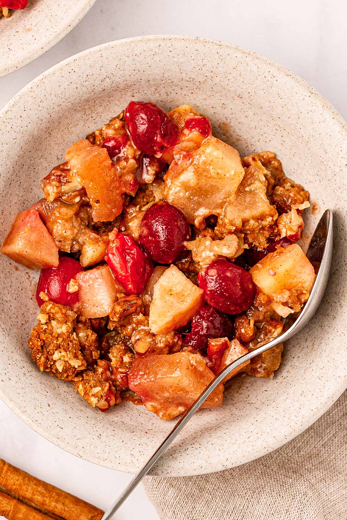 overhead view of cranberry apple crisp in a bowl with a spoon