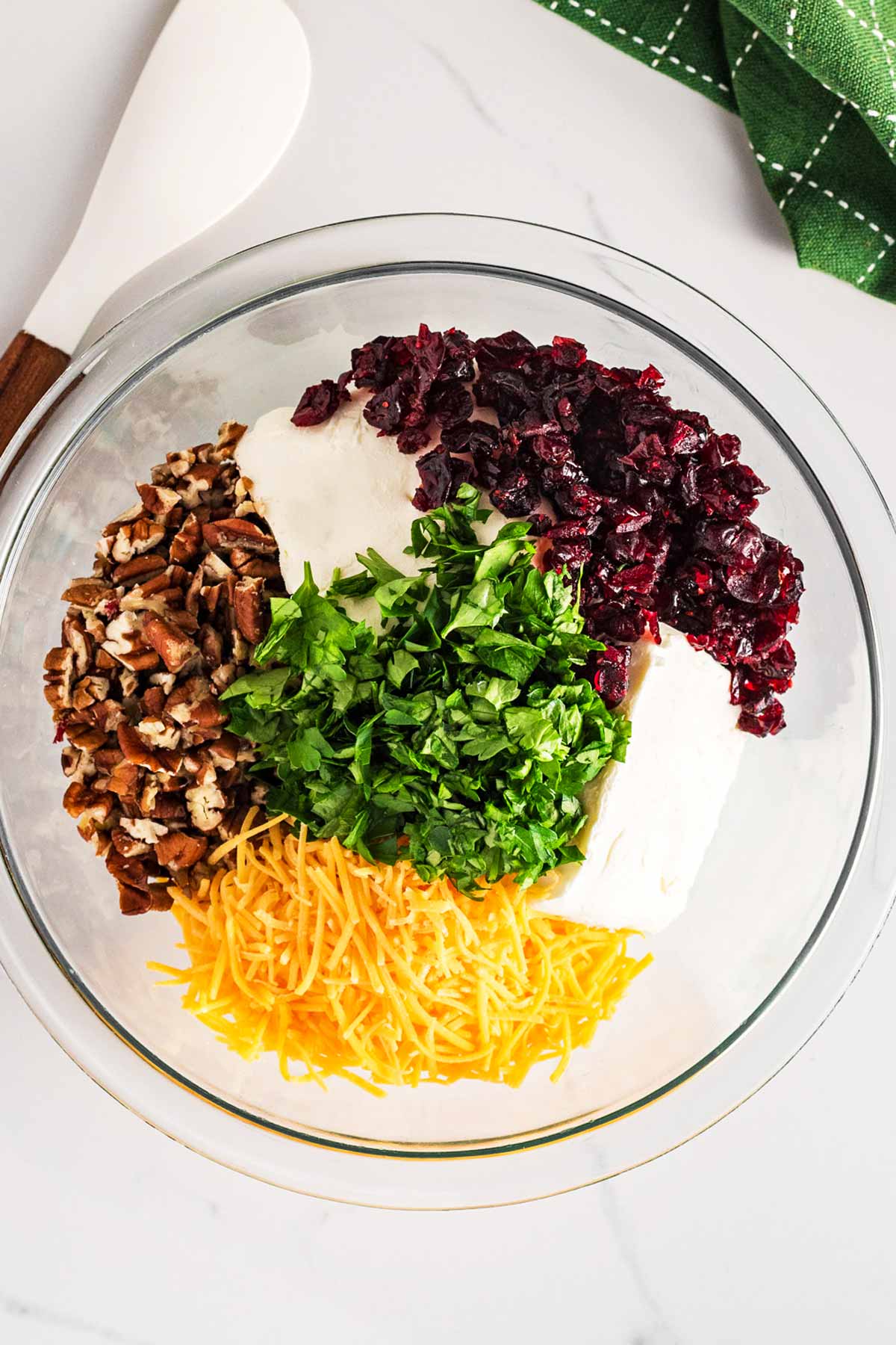 overhead view of ingredients for cranberry pecan cheeseball in glass bowl