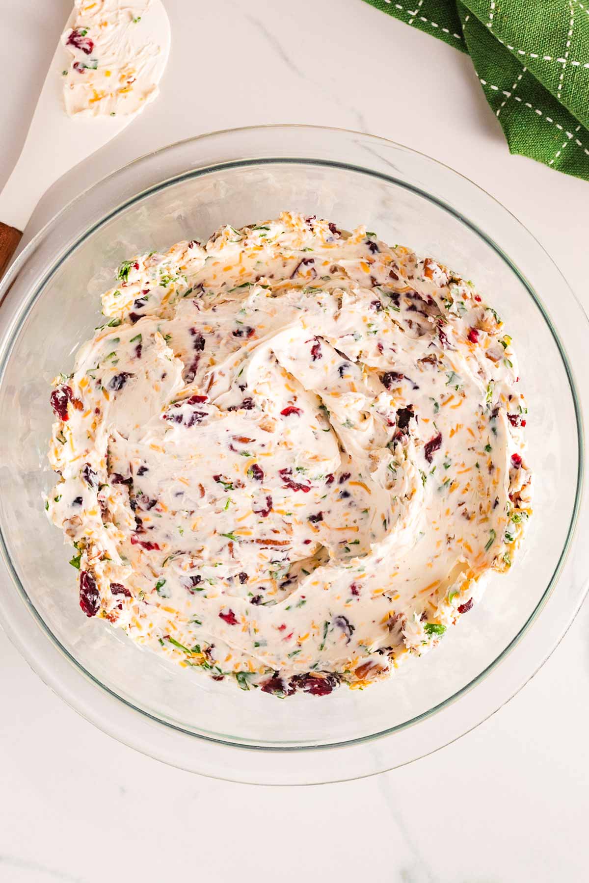 overhead view of mixture for cranberry pecan cheeseball in glass bowl