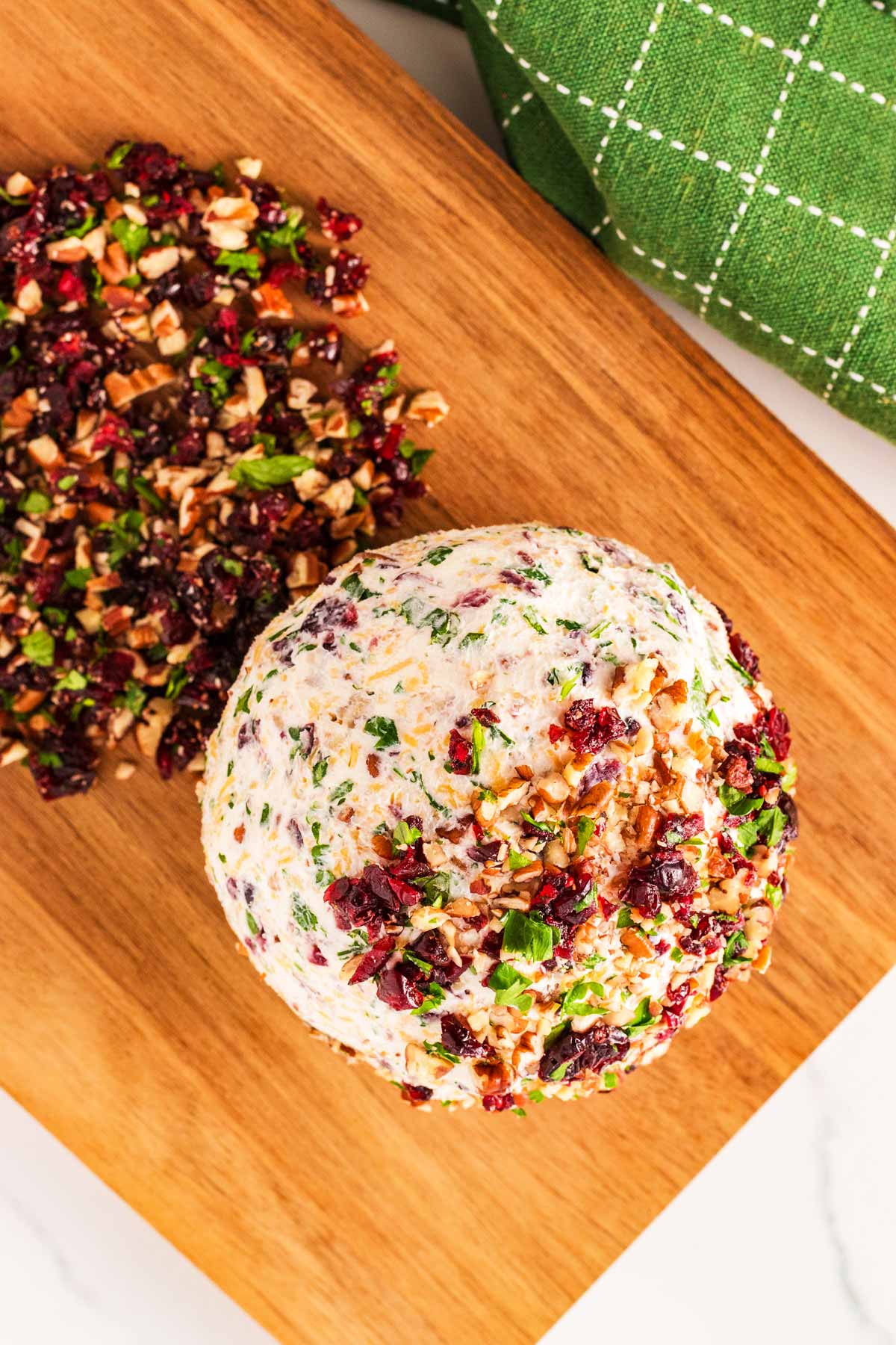 overhead view of cheeseball being rolled in toppings