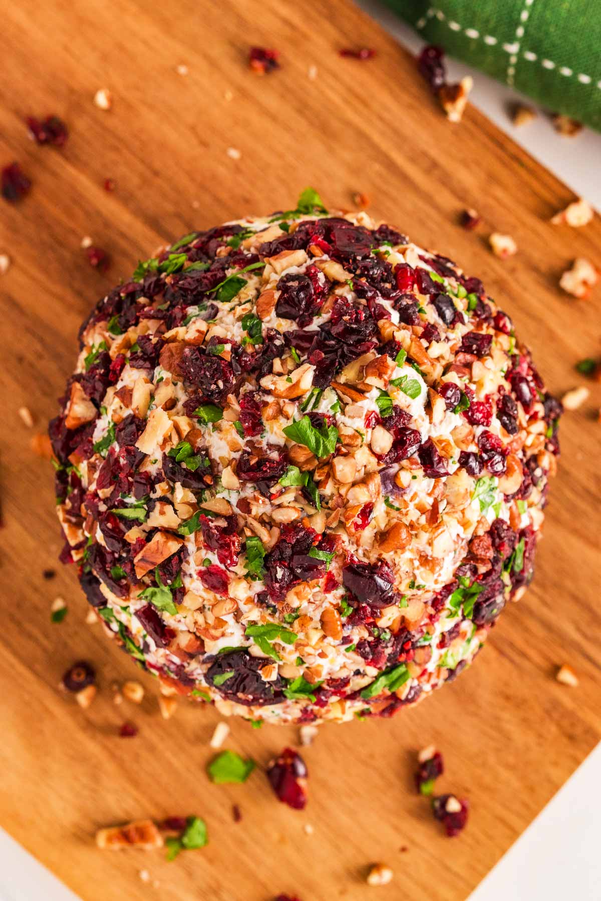 overhead view of cranberry pecan cheeseball on wooden chopping board