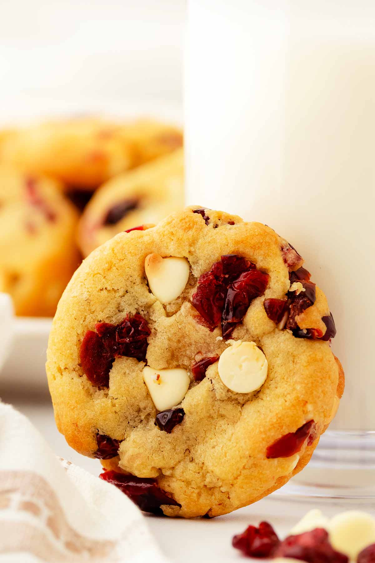 frontal view of cranberry white chocolate chip cookie in front of milk glass