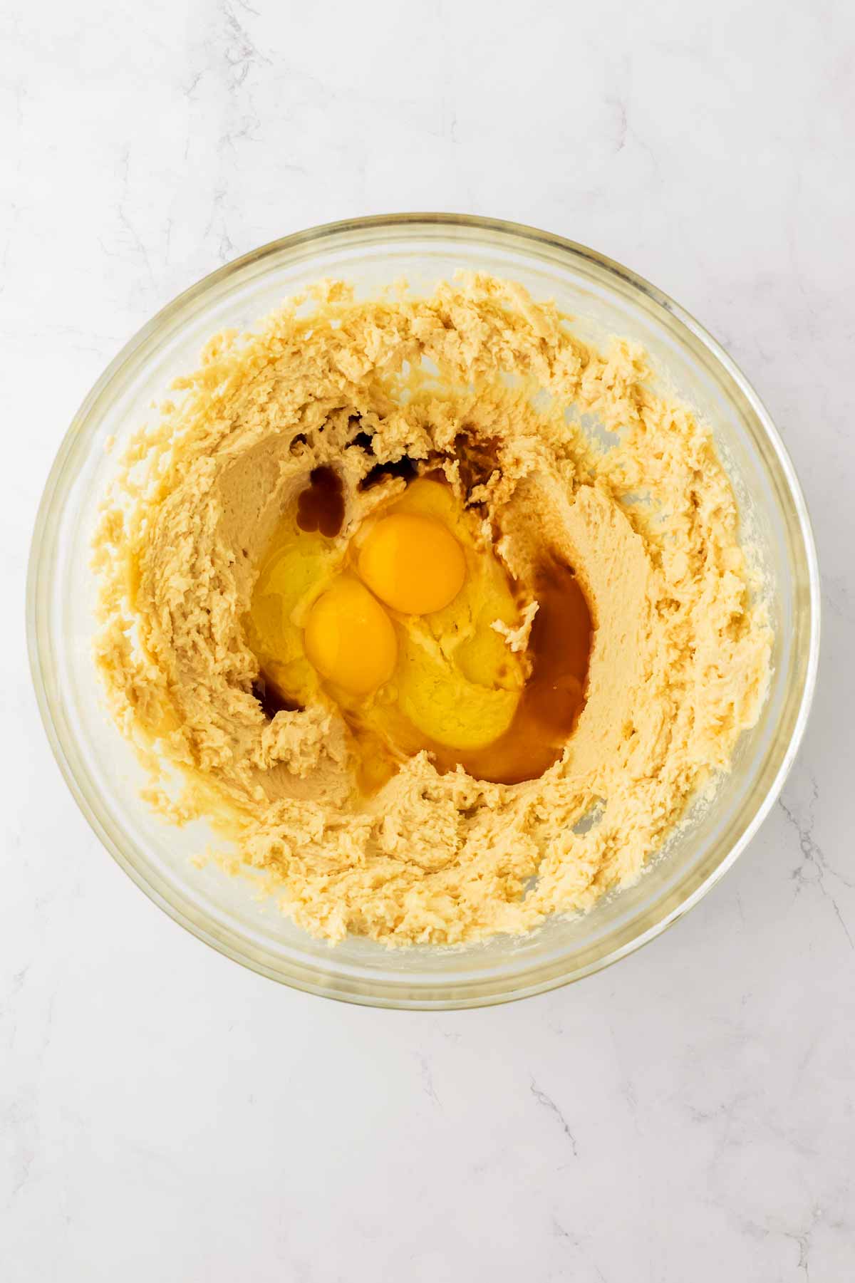 overhead view of eggs in bowl with creamed cookie ingredients