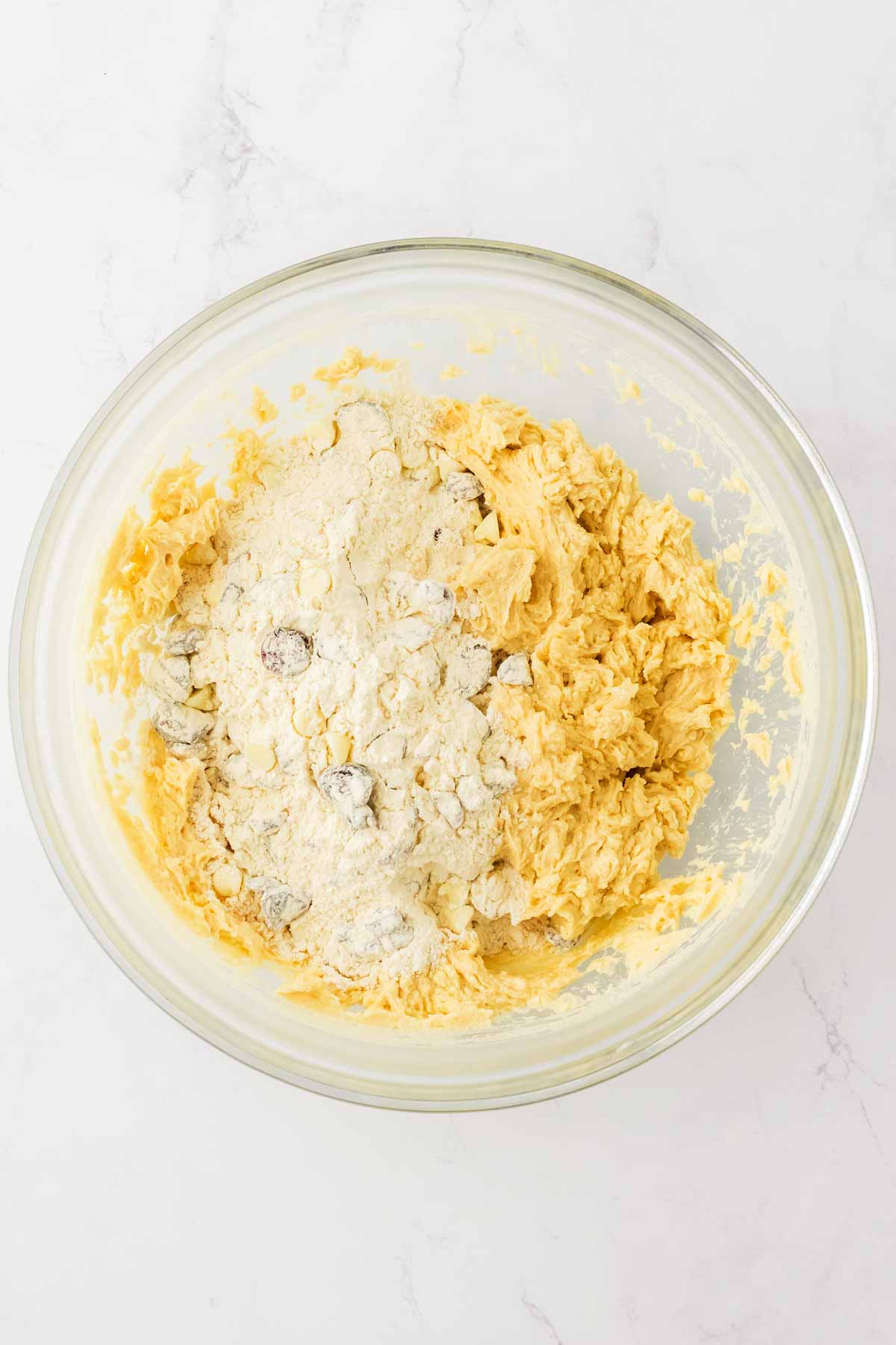 overhead view of creamed ingredients and flour in glass bowl