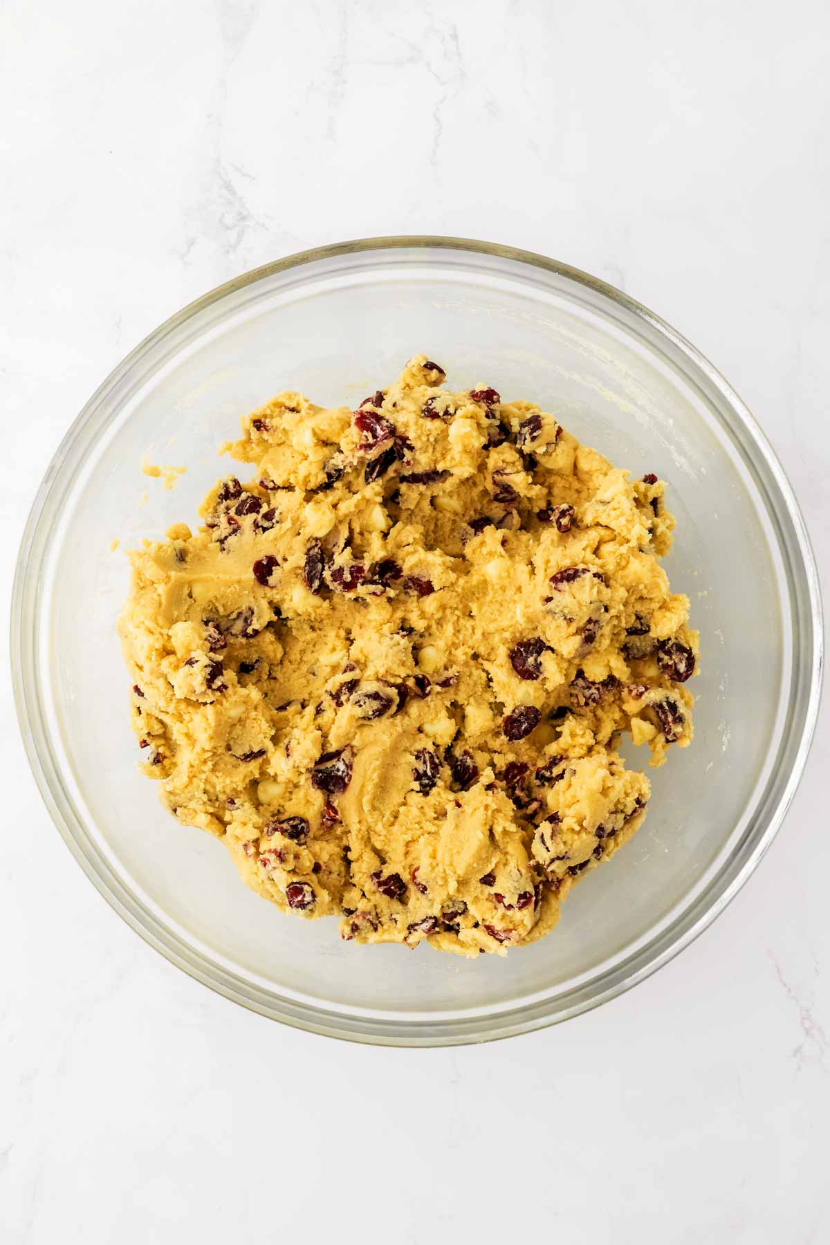 overhead view of cranberry white chocolate chip cookie dough in glass bowl