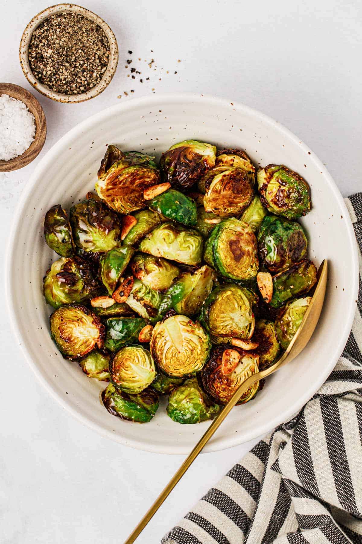 overhead view of roasted Brussels sprouts in a white bowl with a spoon