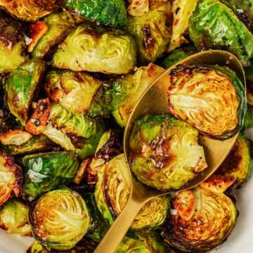 overhead view of roasted Brussels sprouts in a white bowl with a spoon