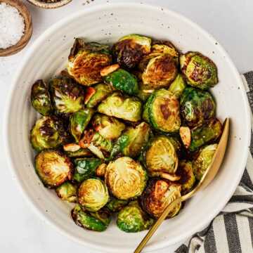 overhead view of roasted Brussels sprouts in a white bowl with a spoon