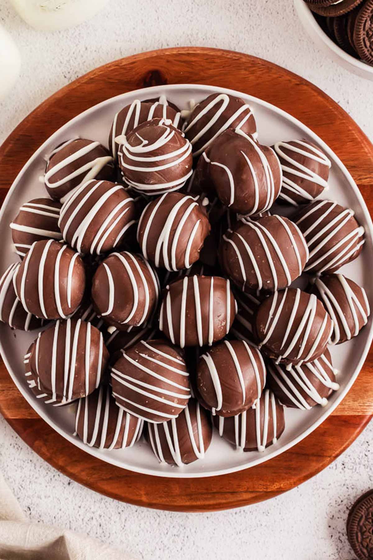 overhead view of oreo balls on white plate on wooden platter