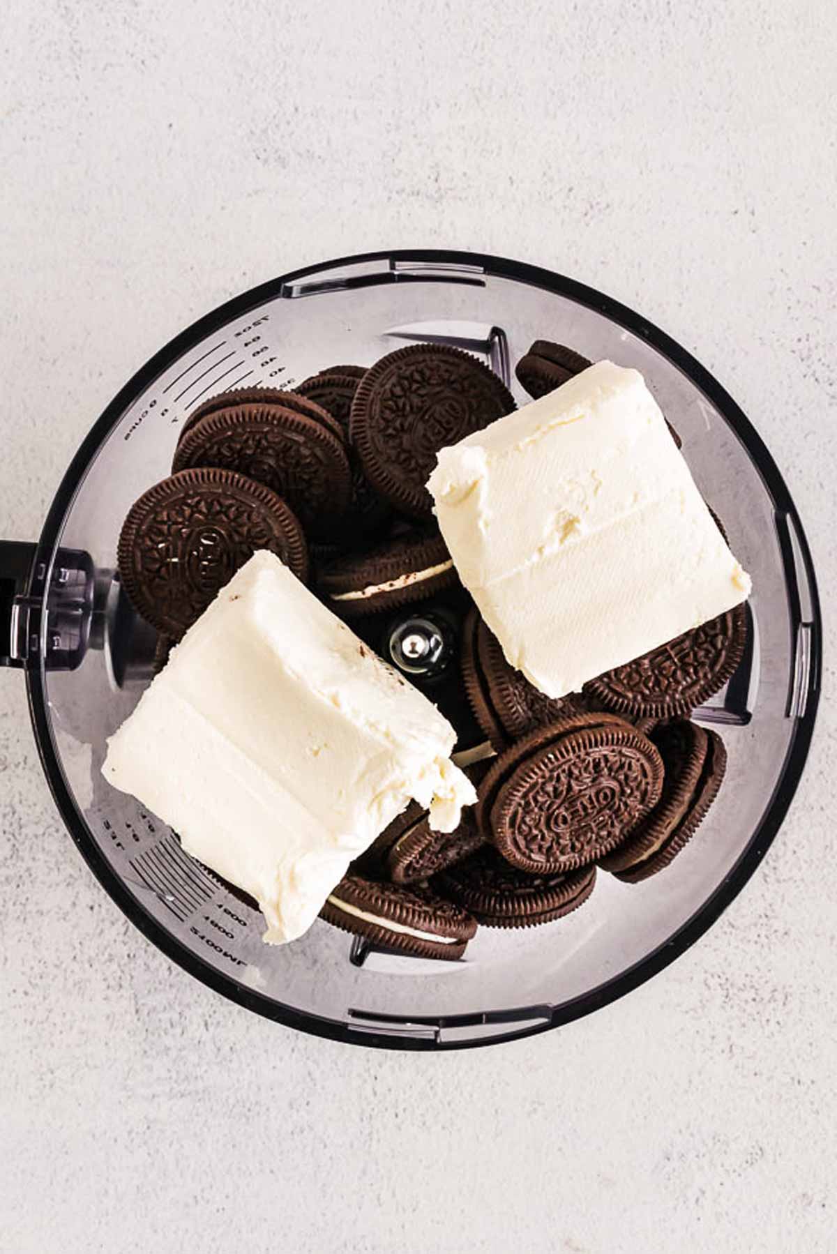 overhead view of Oreos and cream cheese in food processor bowl