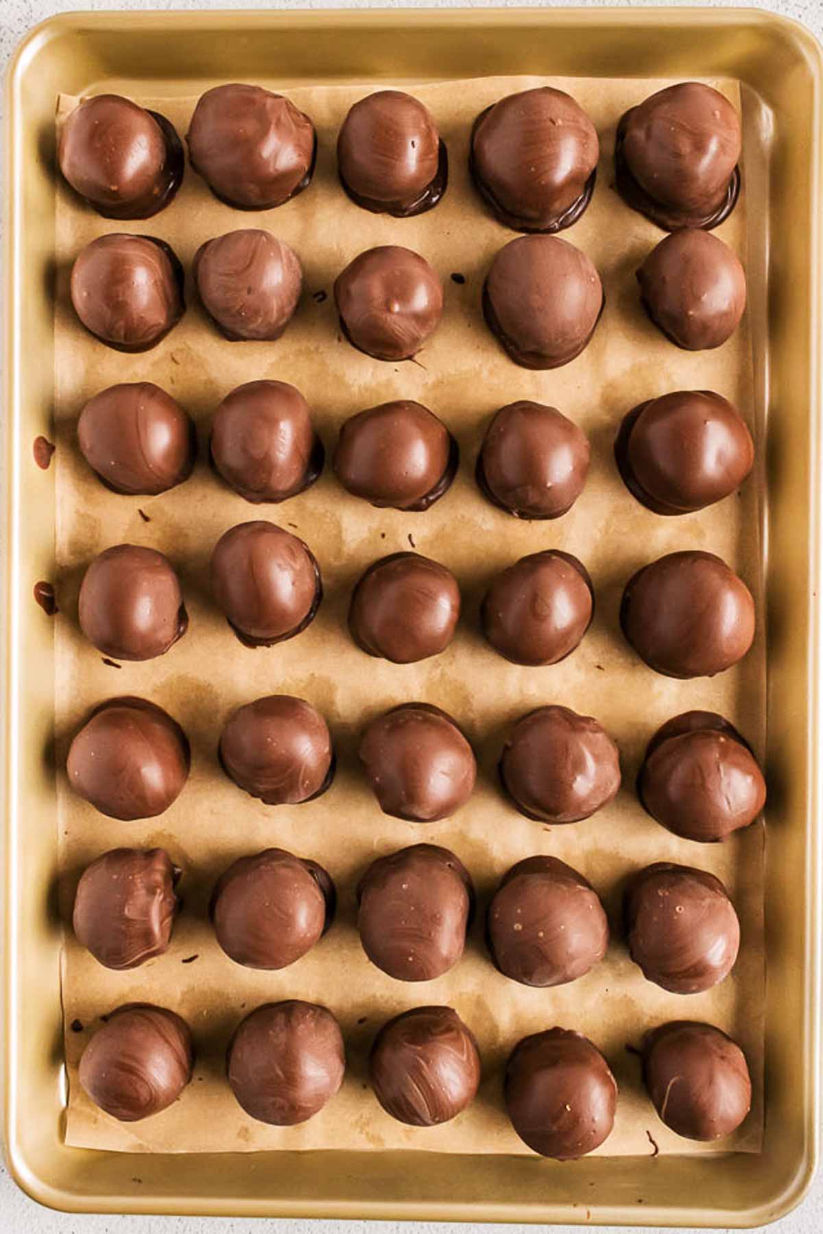 overhead view of chocolate coated oreo truffles on lined baking sheet