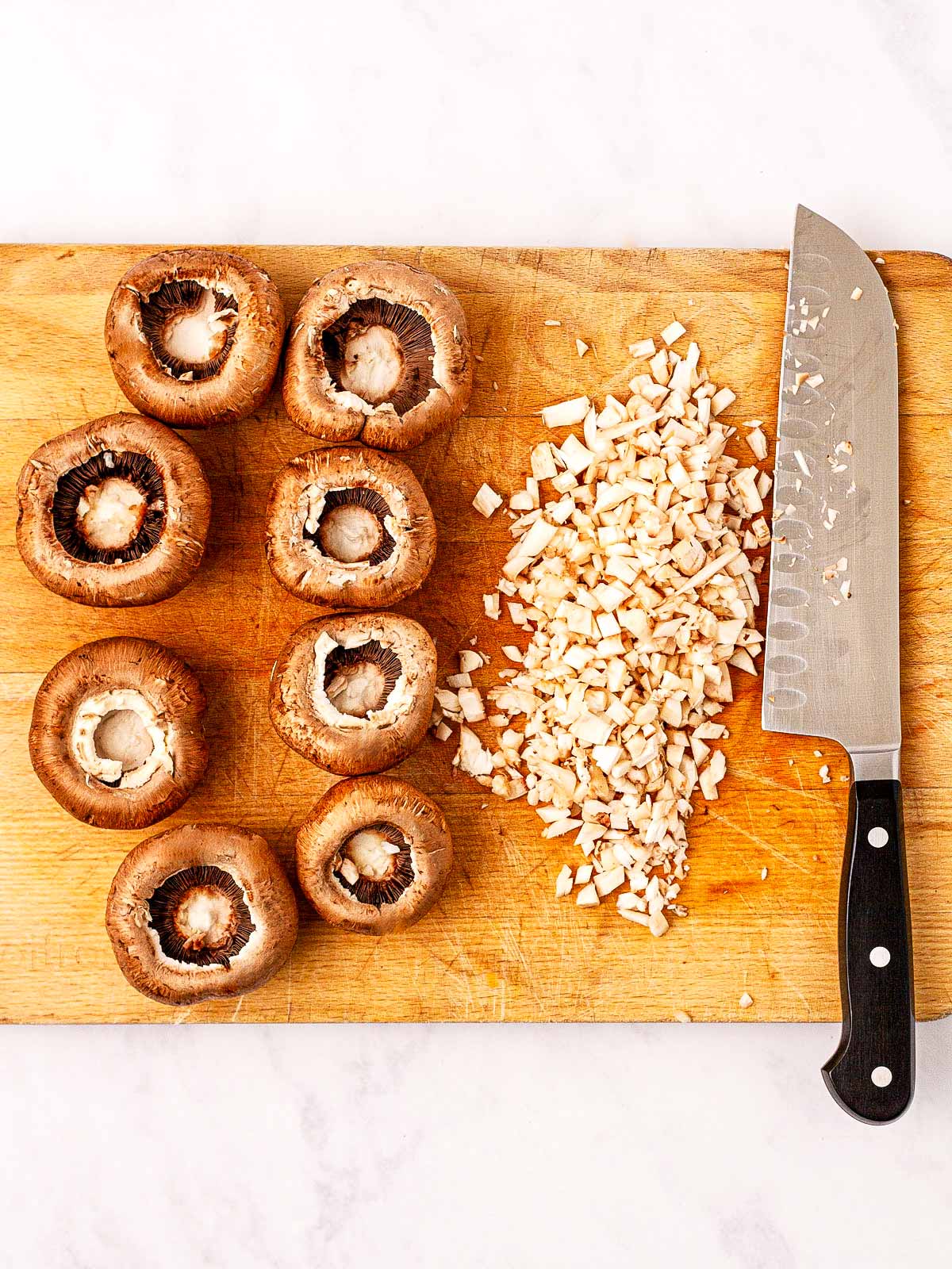 overhead view of mushrooms with chopped stems on wooden cutting board