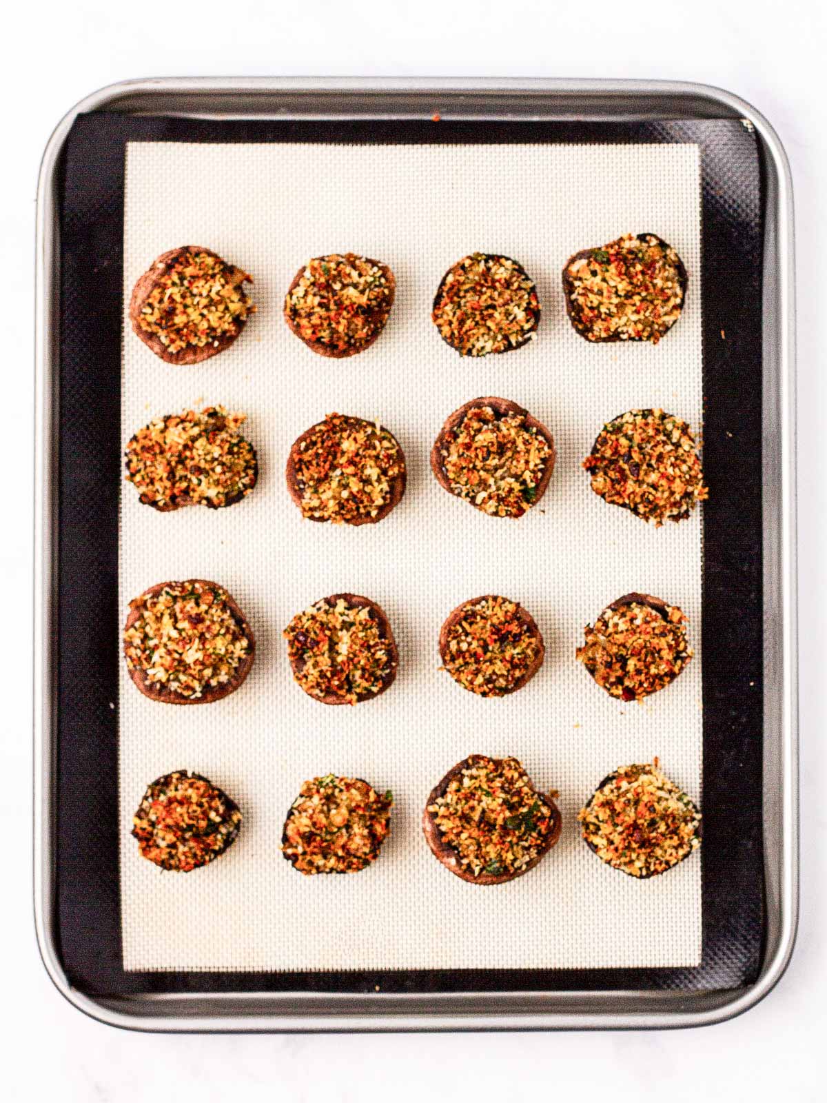 overhead view of baked stuffed mushrooms on lined baking sheet