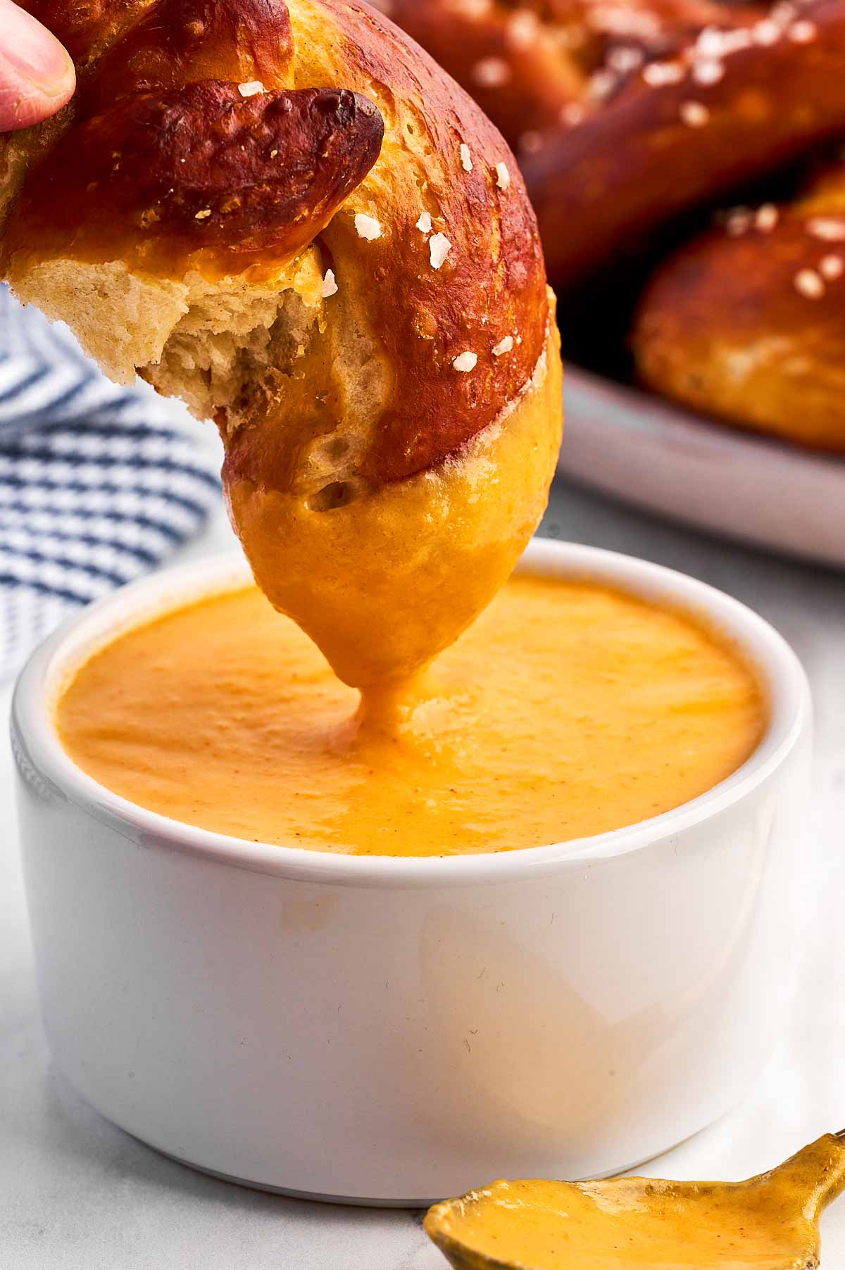 frontal view of pretzel being dipped into beer cheese dip