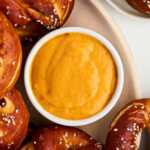 overhead view of beer cheese dip in bowl surrounded by soft pretzels