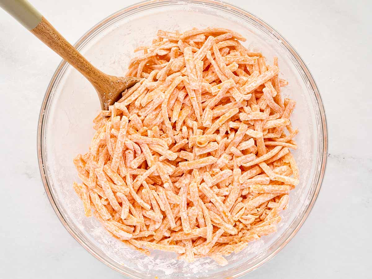 overhead view of shredded cheddar cheese in a bowl with cornstarch